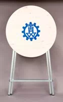 Stehtisch klappbar, mit weiß lasierter Holzplatte zusammengeklappt, mit Logo. Stehtisch zusammengeklappt mit Logo